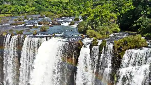Man Tightroping Through Rainbow Above Waterfall